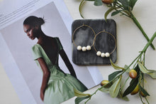 Load image into Gallery viewer, Our Terra earrings are classic, minimalist earrings featuring lightweight wooden beads on each hoop. The beads rest on our signature, Orbis hoops, handcrafted from 14k gold-filled wire.  These earrings are delicate, airy and understated... they are sure to attract attention!   The large hoops measure approximately 2 inches in diameter. The small hoops measure approximately 1.5 inches in diameter.